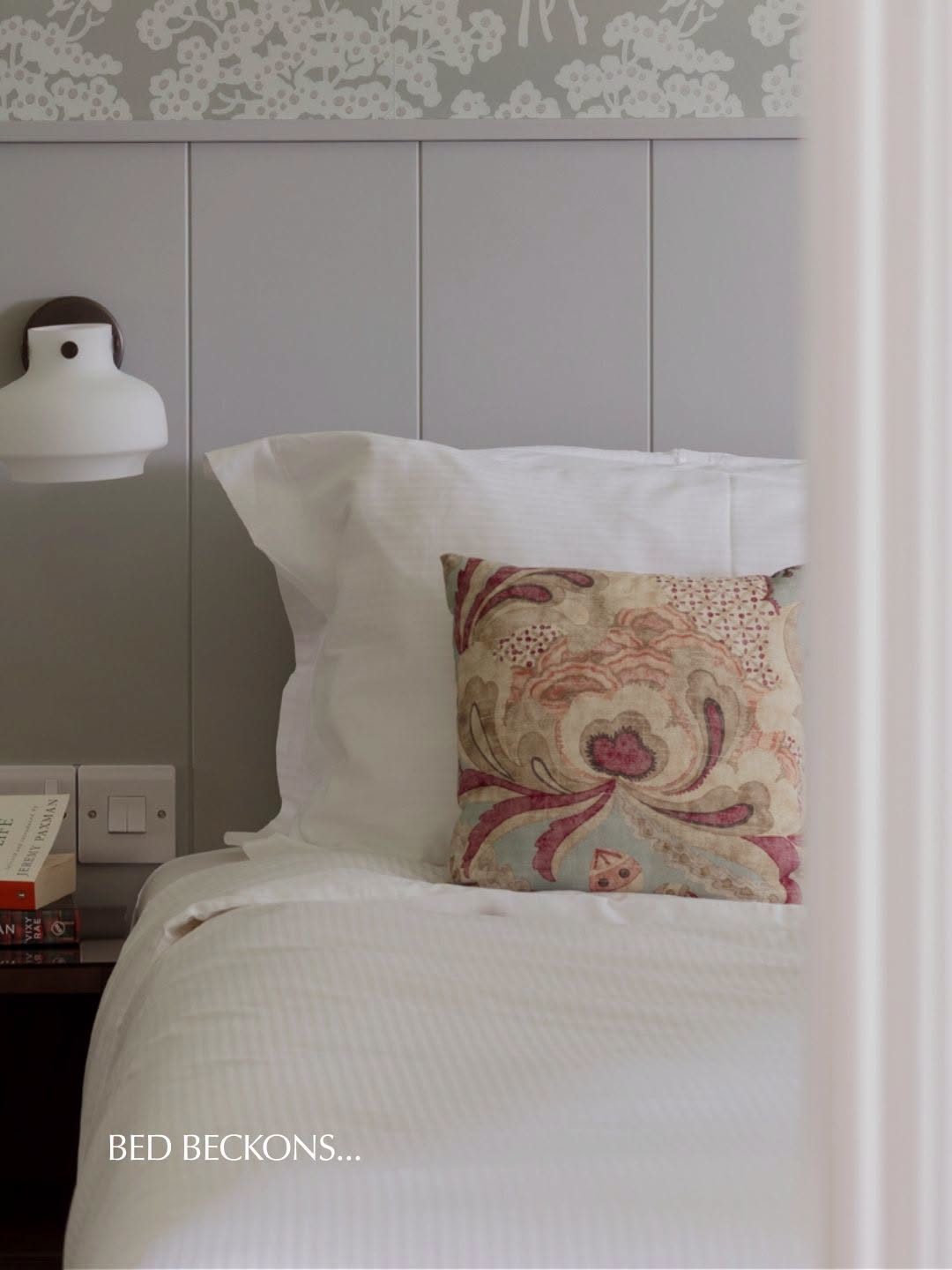 A crisp made-up bed in a lodge bedroom, reading Bed Beckons