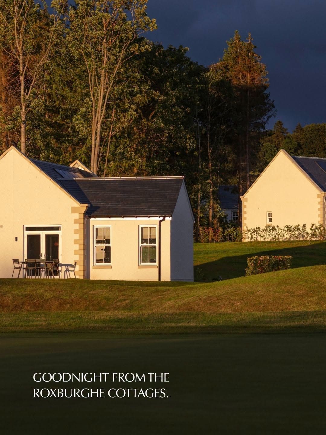 Evening light on the stone lodges at Schloss Roxburghe with dark storm clouds behind